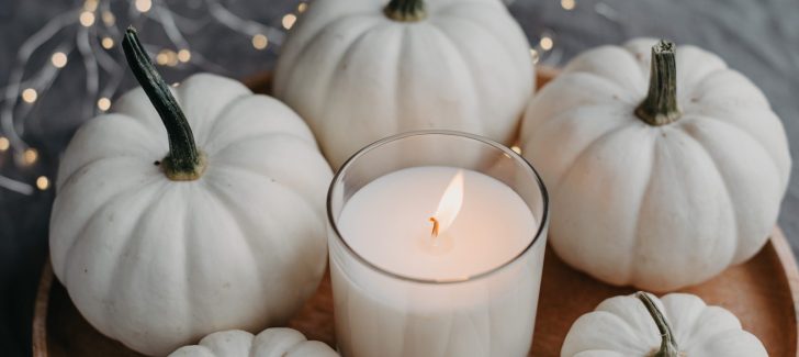 White pumpkins surrounding candle