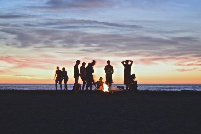 A group of people on a beach with a sunset in the background